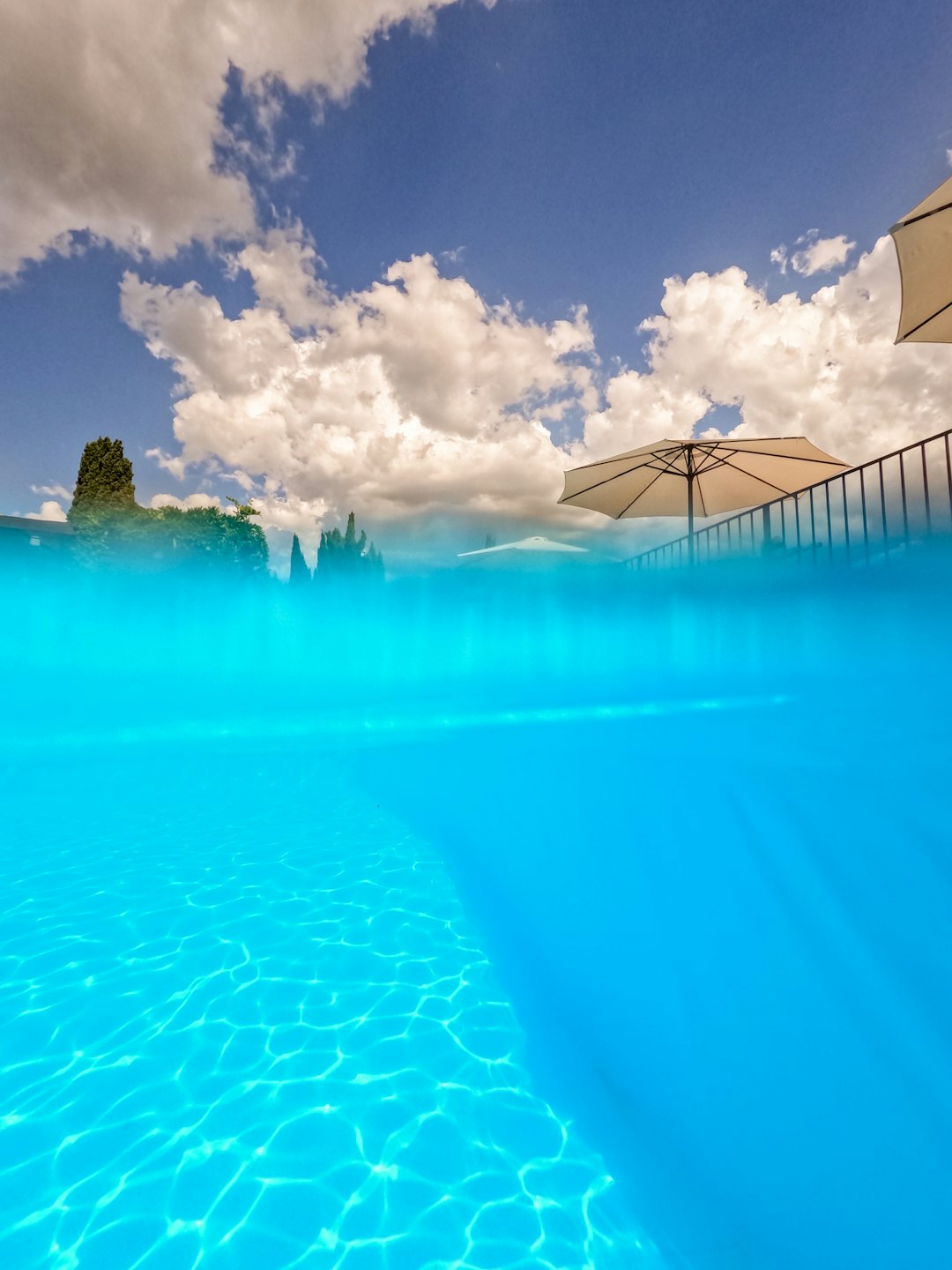 Crystal clear swimming pool water below a sunny resort patio.