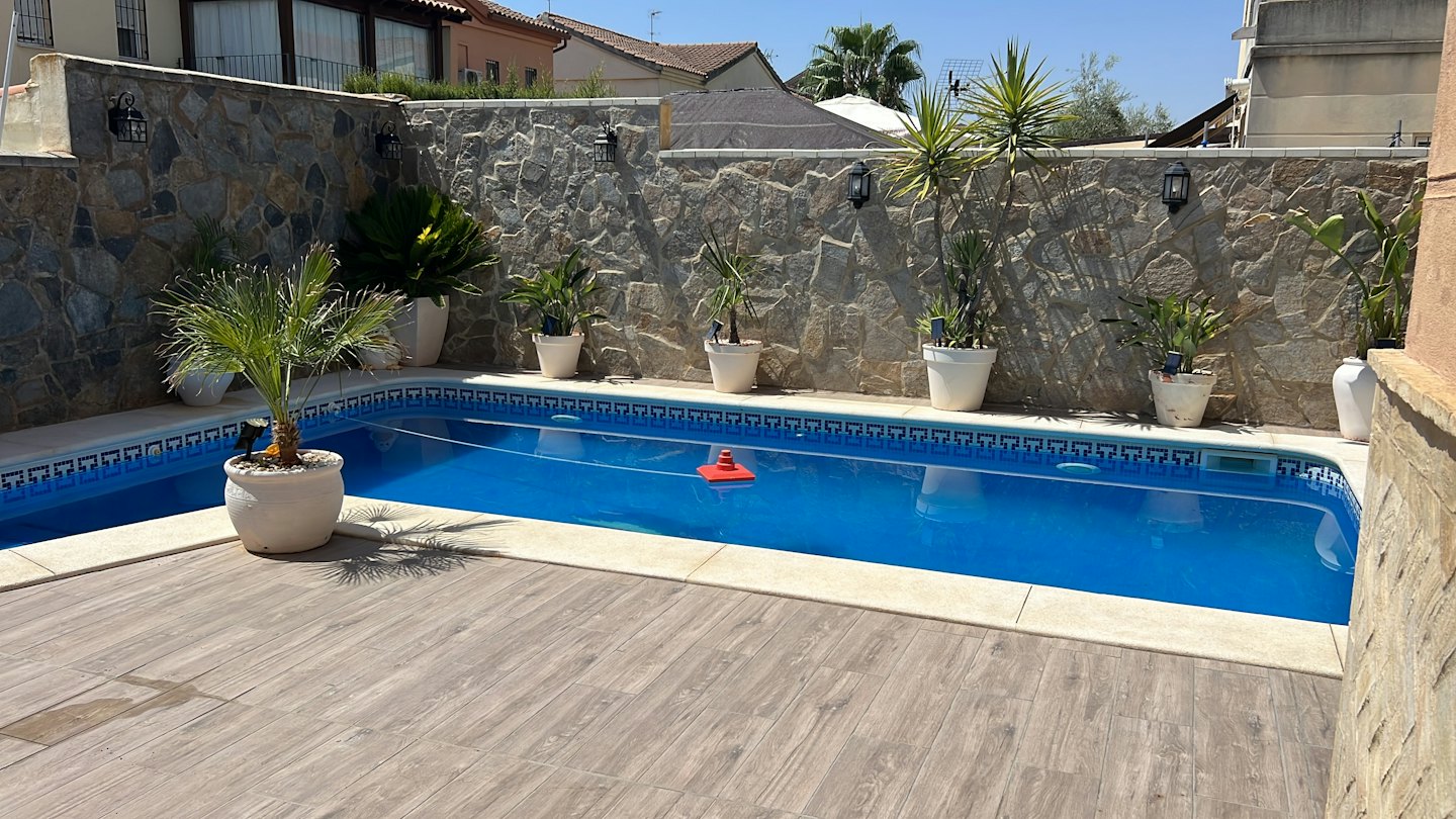 A red pool cleaner floats in a backyard swimming pool.