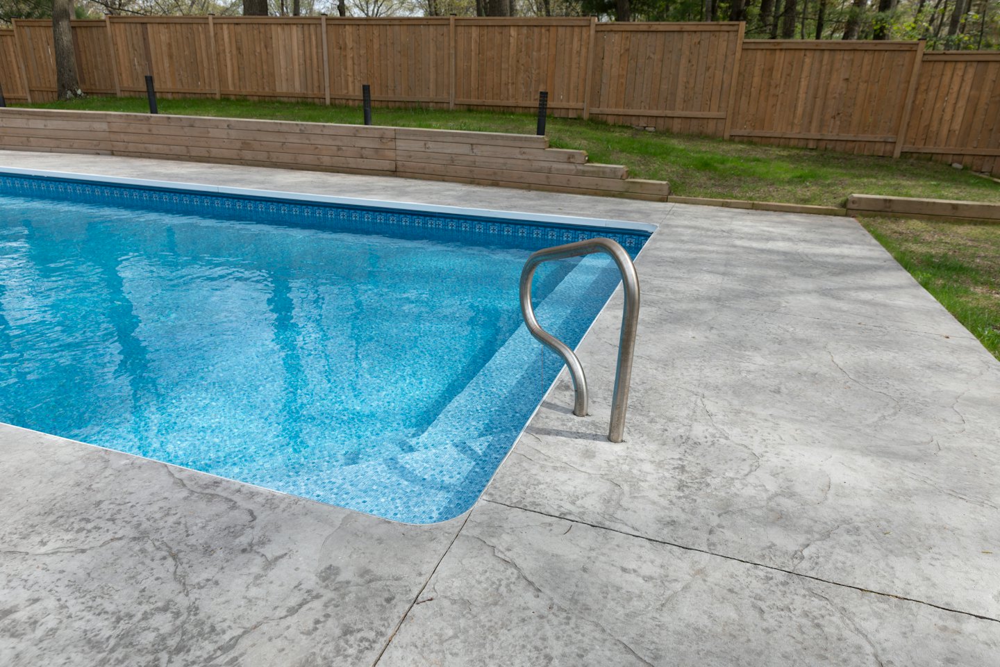 An in-ground swimming pool with a stainless steel ladder.